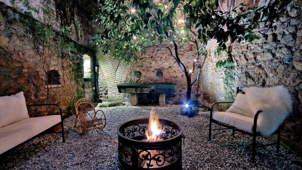 An outdoor seating area with a fire pit, stone walls, and a rustic ambiance. - San Callisto - WR Apartments (Rome)