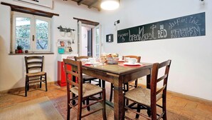 A dining area with a wooden table and chairs, a window with a view, and a wall sign. - San Callisto - WR Apartments (Rome)