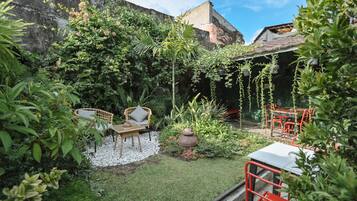 Un jardín con zona de estar, una pequeña mesa y una planta en maceta.