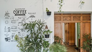 A wall with an illustrated coffee processing guide and a wooden door. - Snooze Guesthouse Yogyakarta - Hostel (Yogyakarta)
