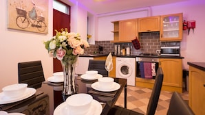 A modern kitchen with wooden cabinets, a built-in oven, and a washing machine. - Landmark Apartments Harrogate (Harrogate)