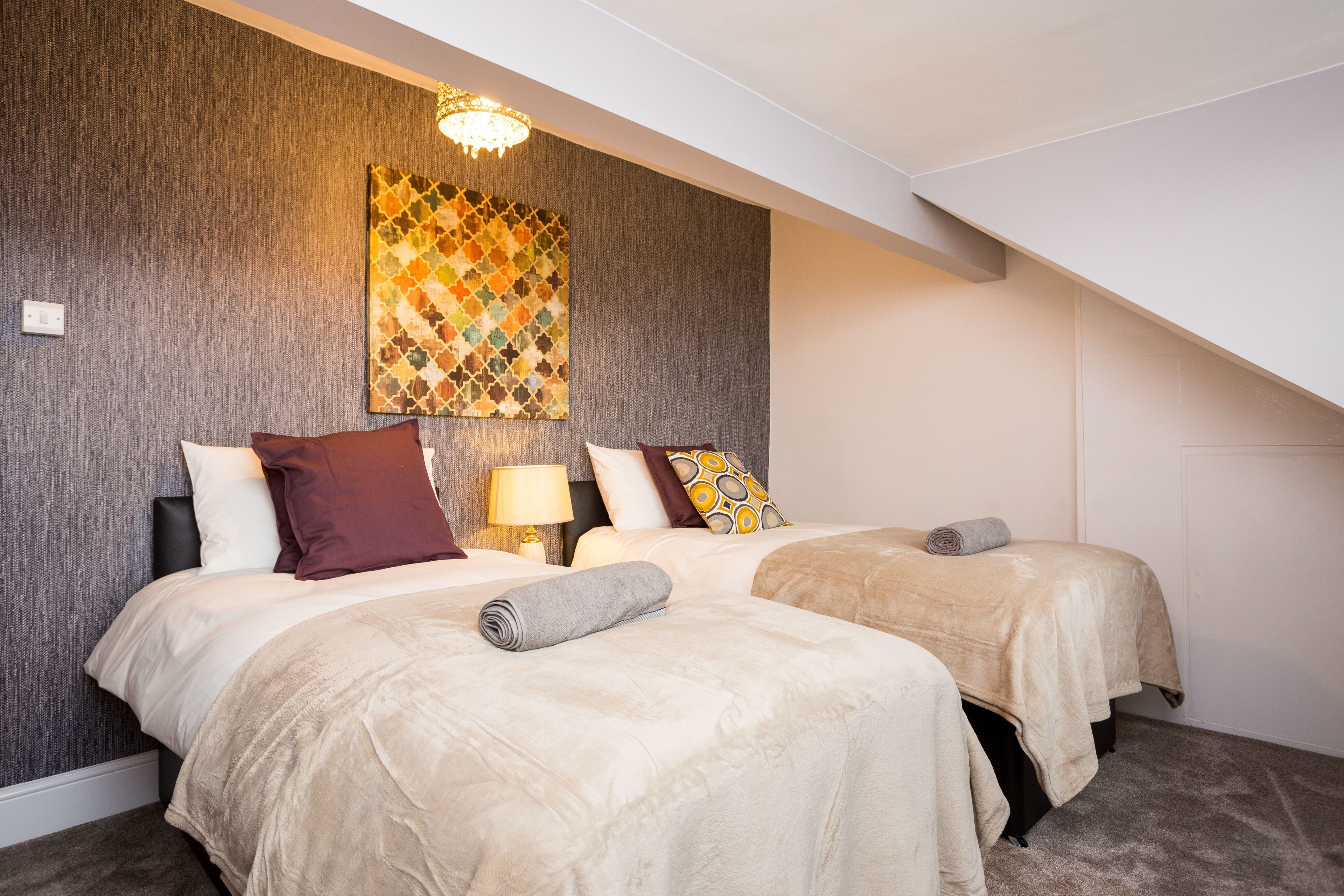 Ein Hotelzimmer mit zwei Betten, einer Wanddekoration mit Muster und einer Chandelüster.