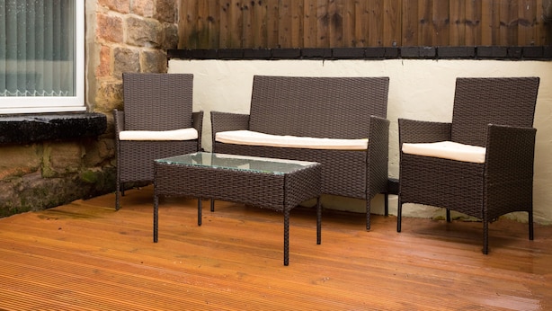 A wicker furniture set with cushions, a glass-top table, and a brick wall backdrop. - Landmark Apartments Harrogate (Harrogate)