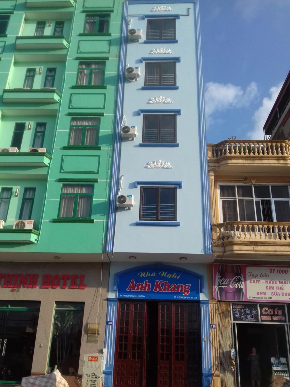 Un edificio de varios pisos con fachada azul y verde, que muestra un cartel de 