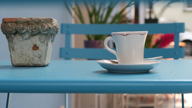A white ceramic cup with a saucer on a blue table. - Piccolo Hotel (Muralto)