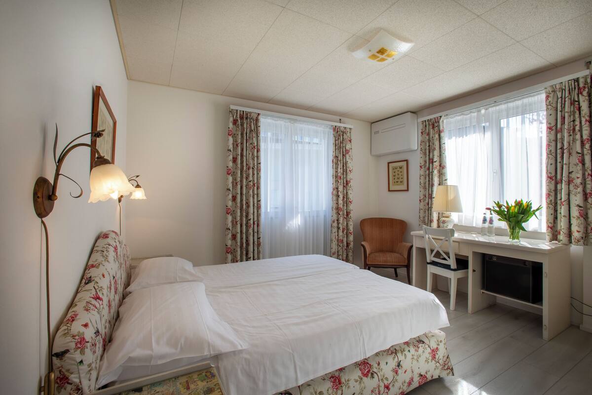 A hotel room with a bed, desk, chair, and a small television.