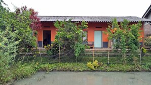 A building with a red and orange facade, a door, and a small porch area. - Asparin Homestay (Banyuwangi)