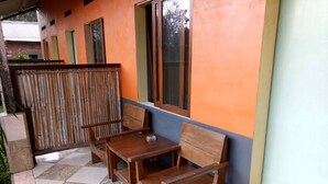 A wooden bench and table set against a building with orange and blue walls. - Asparin Homestay (Banyuwangi)
