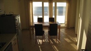 Et værelse med et bord og stole foran et stort vindue med gardiner.