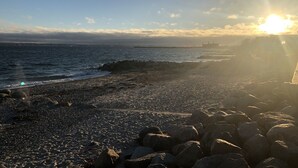 A rocky beach with the sun setting over the horizon. - Danhostel Helsingør Vandrerhjem (Helsingor)