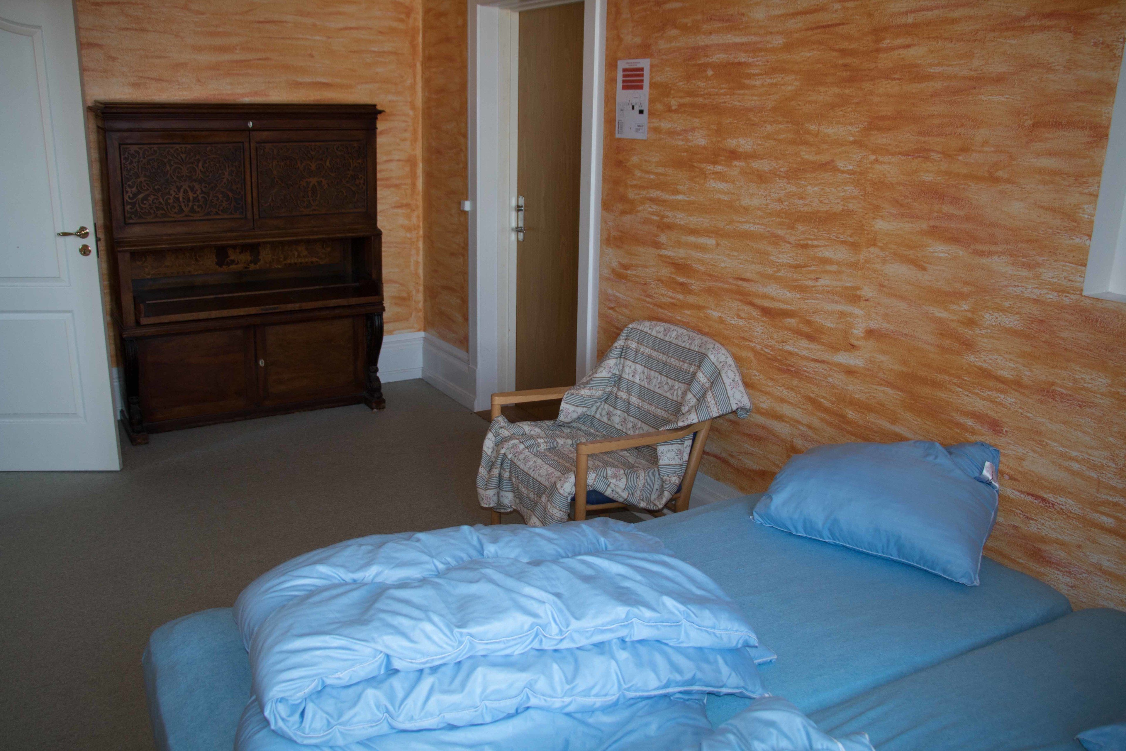Ein Schlafzimmer mit einem Bett, einem Sessel, einem Kleiderschrank und einer Tür.