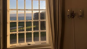 A room with a large window offering a view of the sea and a grassy area. - Danhostel Helsingør Vandrerhjem (Helsingor)