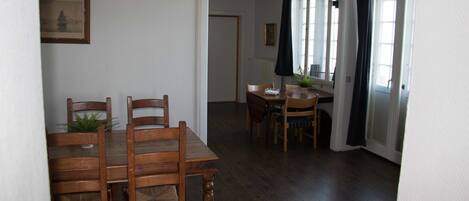 A dining area with wooden tables and chairs, a potted plant, and a framed picture on the wall.