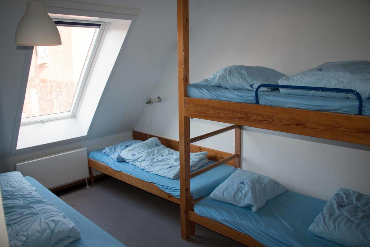 Ein Schlafsaalzimmer mit Etagenbetten, einem Dachfenster und einer Heizung.