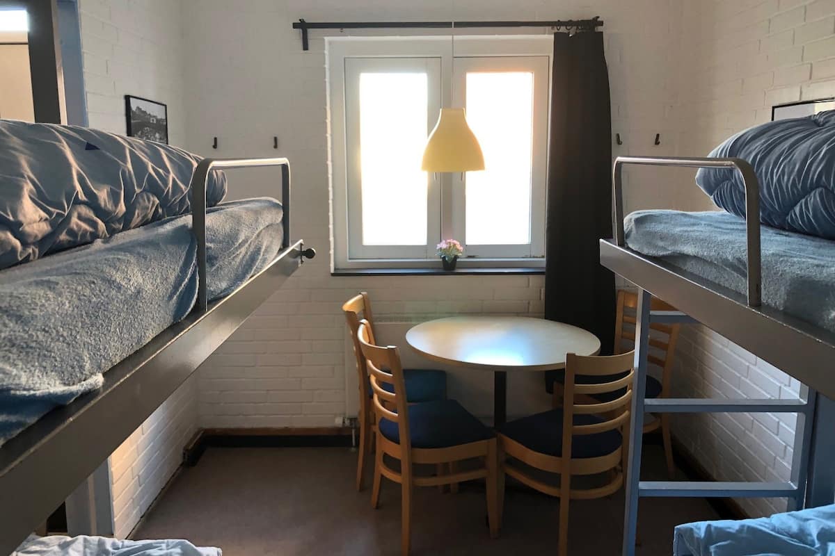 Ein Schlafsaalzimmer mit Etagenbetten, einem runden Tisch und Stühlen.