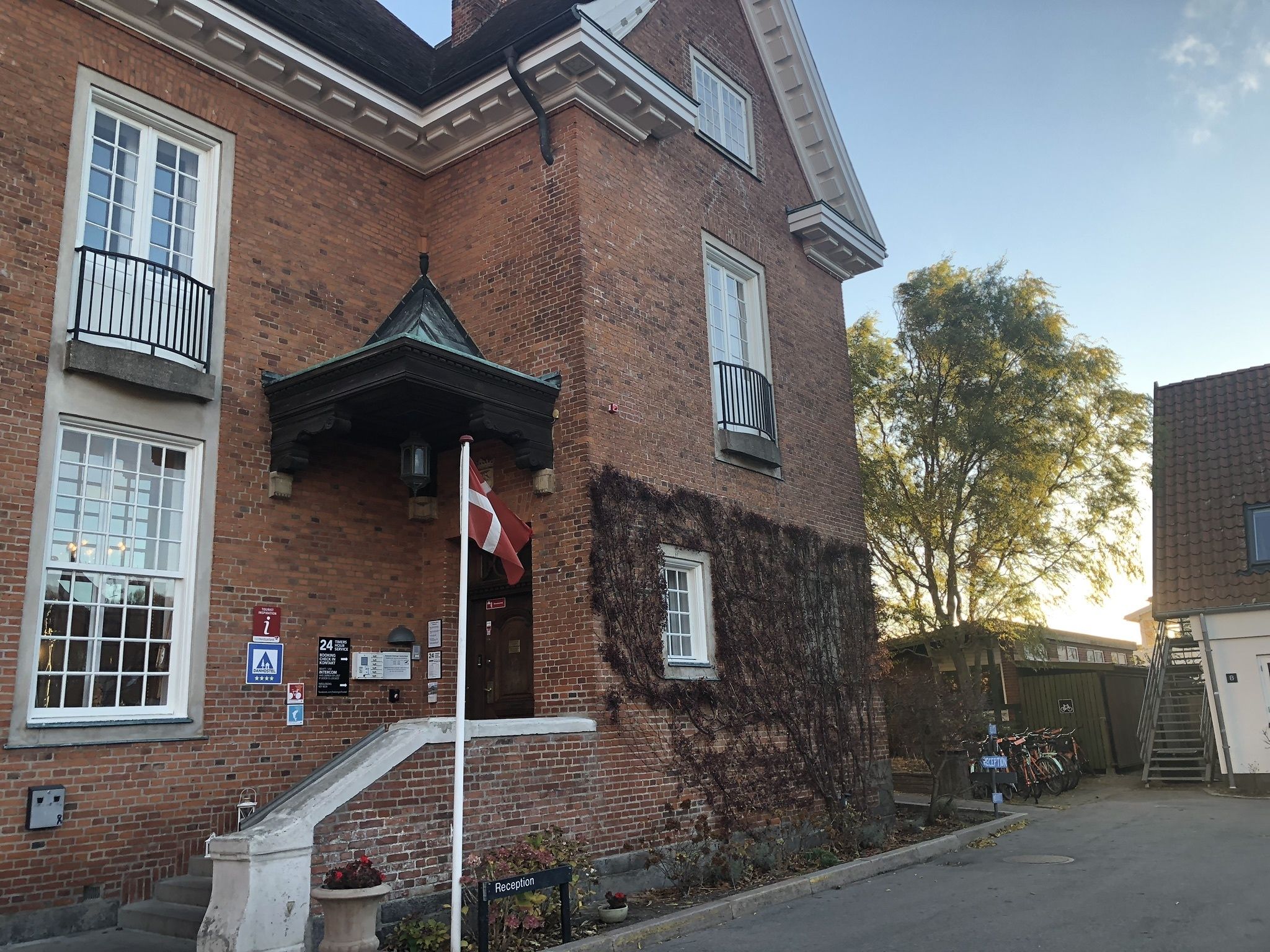 Un edificio de ladrillo con recepción, una escalera y un asta de bandera.