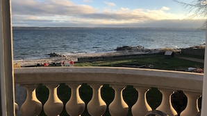 A balcony with a view of the sea, a rocky shoreline, and a small wooden structure. - Danhostel Helsingør Vandrerhjem (Helsingor)