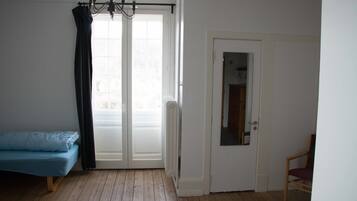 Ein Zimmer mit einem Bett, einem Sessel, einer Tür und einem fensterbepflegten Fenster.