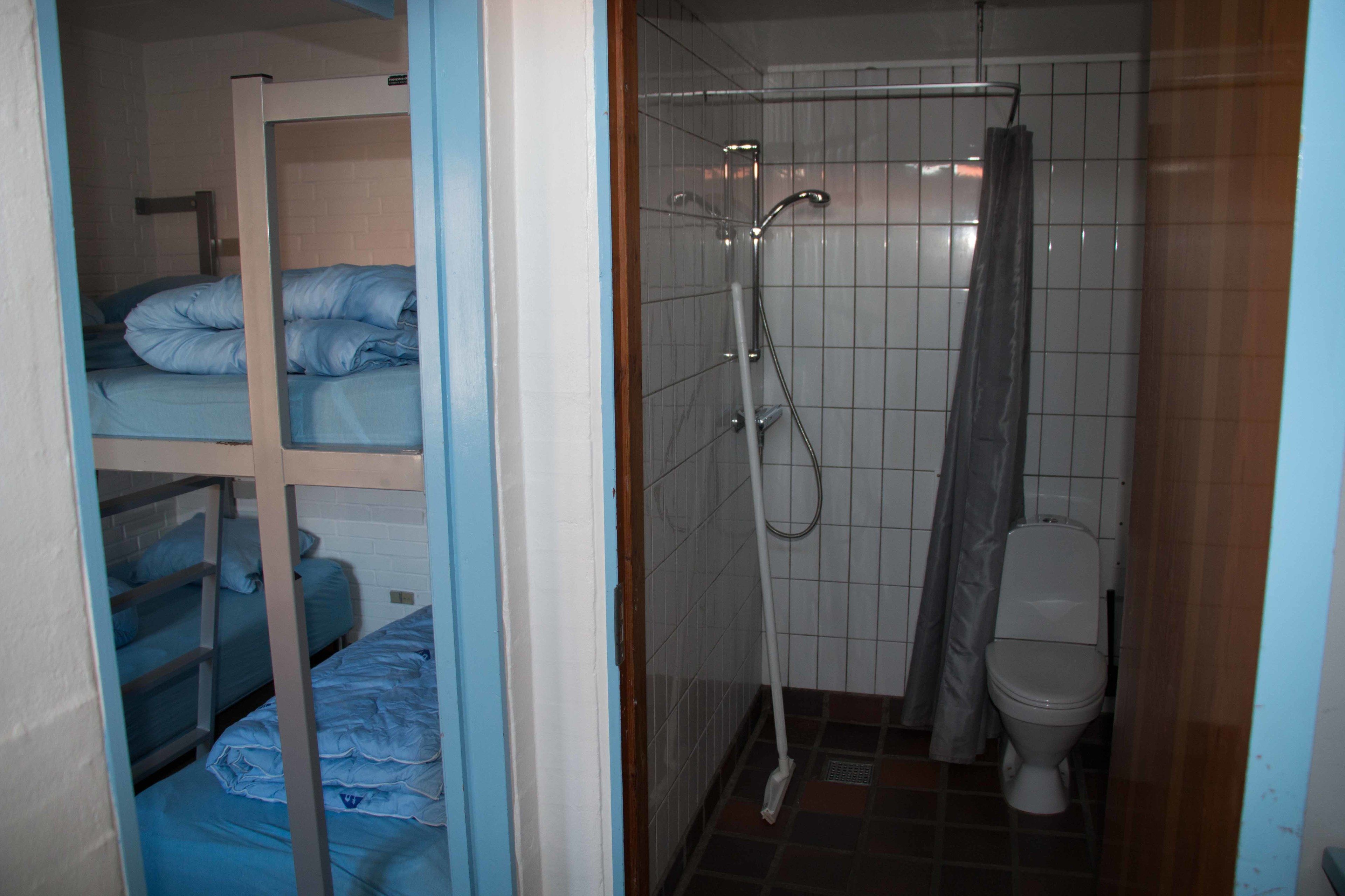 A small, compact bathroom with a shower, toilet, and bunk beds.