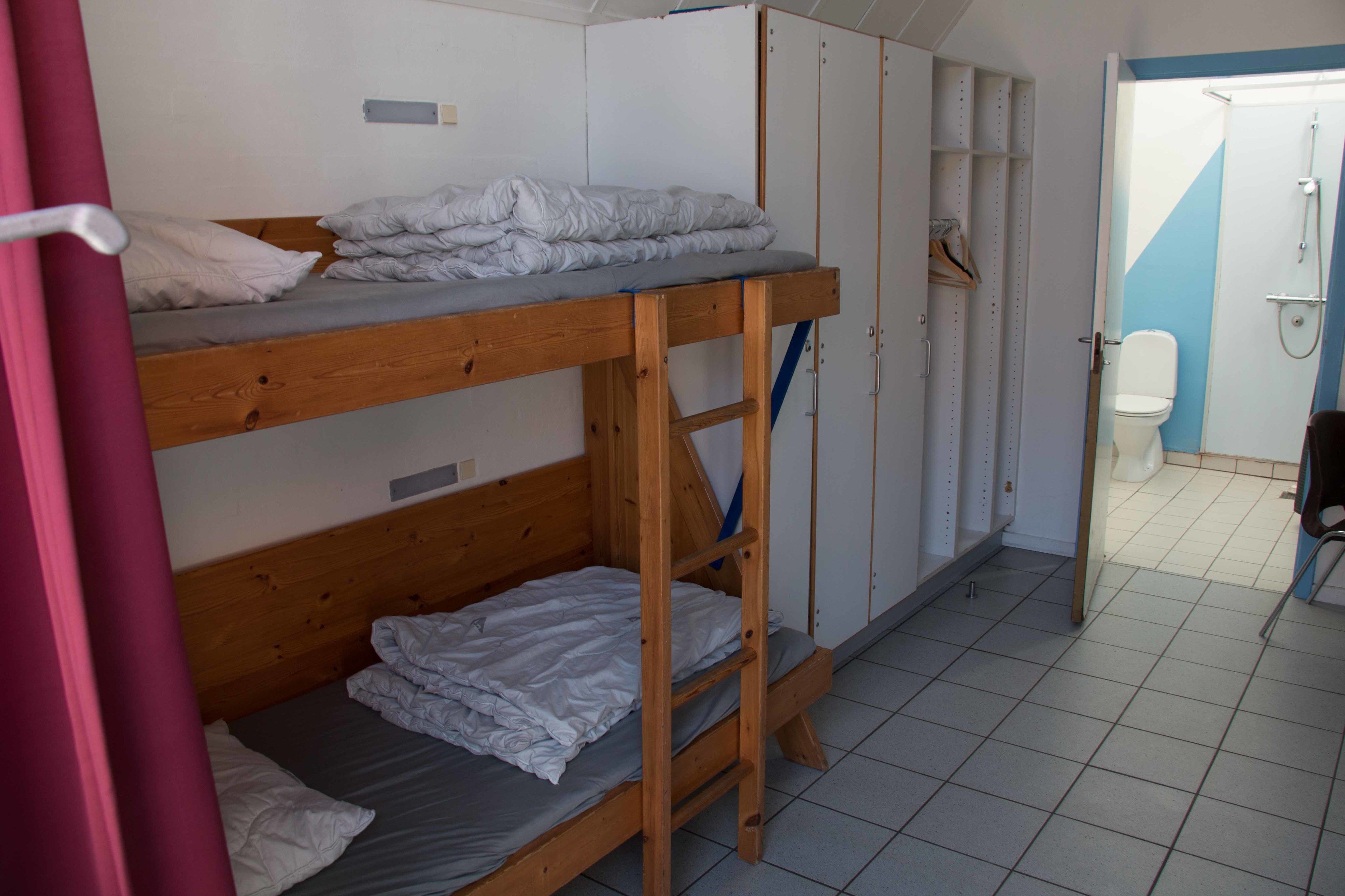 Habitación tipo dormitorio con literas, un armario y un baño con ducha.