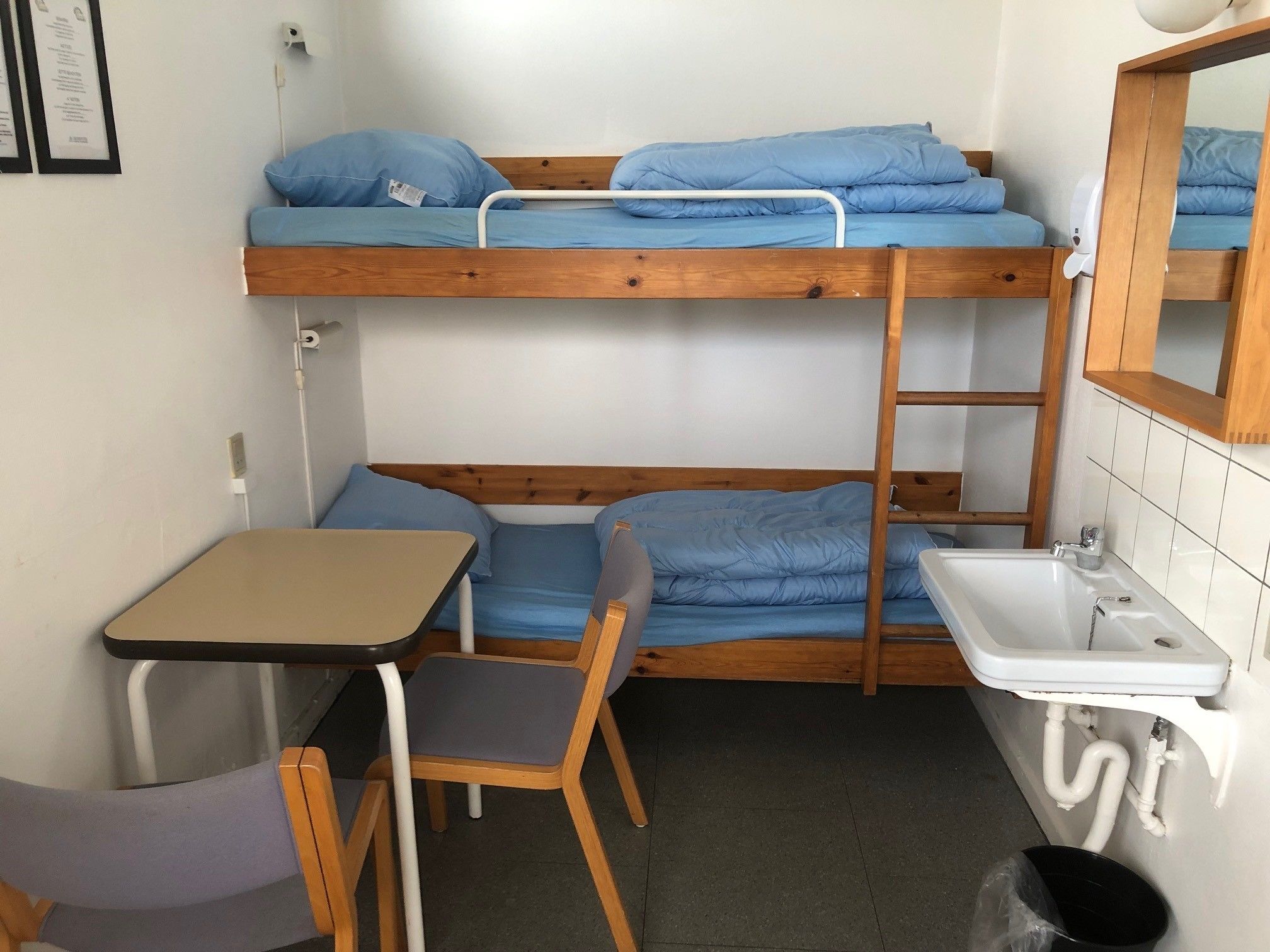 Dormitorio con literas, un lavamanos y una mesita.