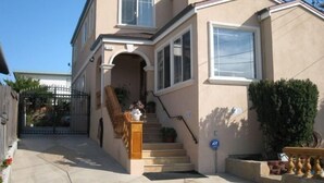 A two-story house with a front entrance, a staircase, and a gated driveway. - Comfortable Vacation Home Near ~SFO~ Airport (San Bruno)