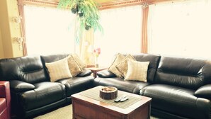 A living room with two black leather sofas, a wooden coffee table, and a green rug. - Comfortable Vacation Home Near ~SFO~ Airport (San Bruno)