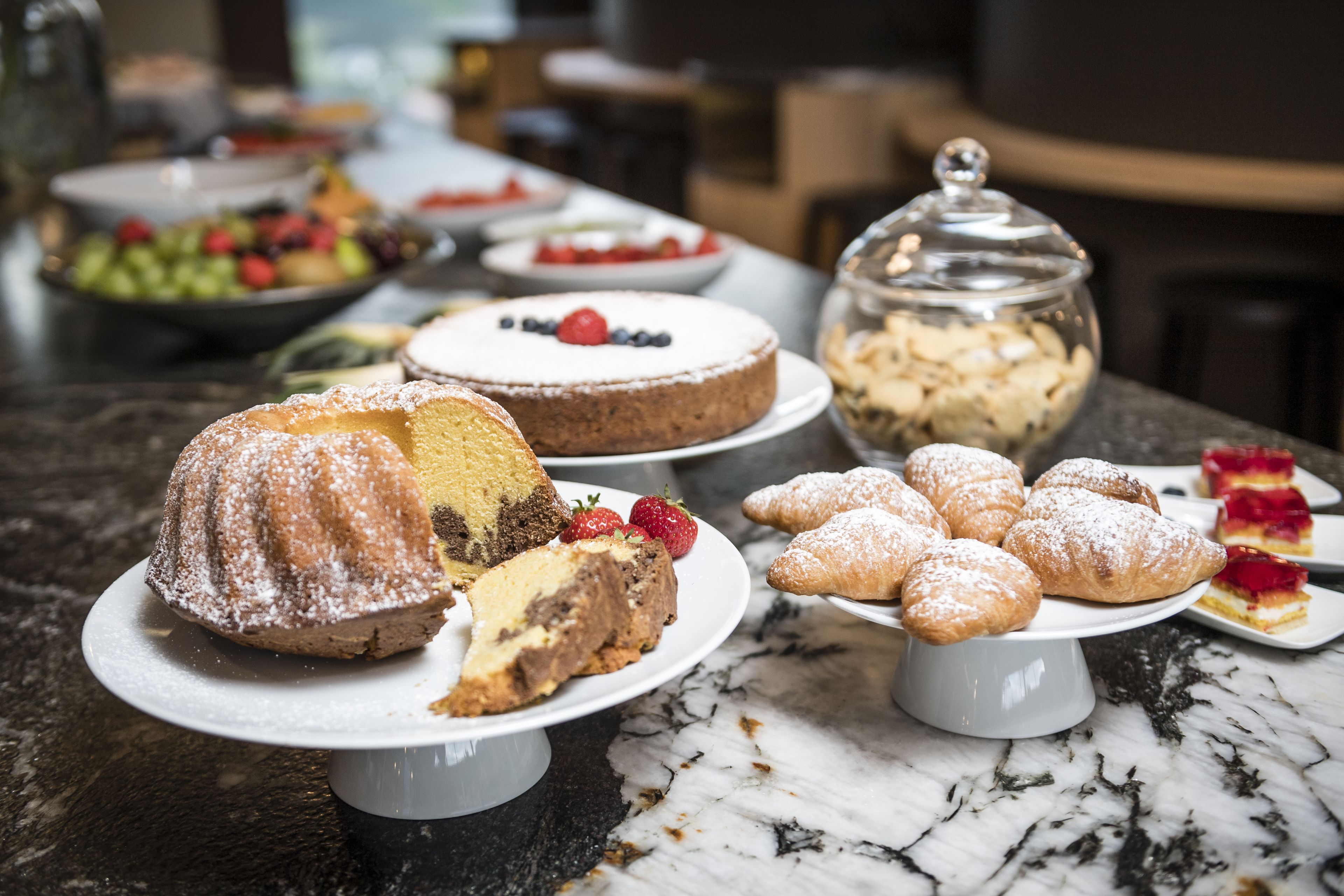 A variety of desserts on display, including cakes, pastries, and a fruit salad.