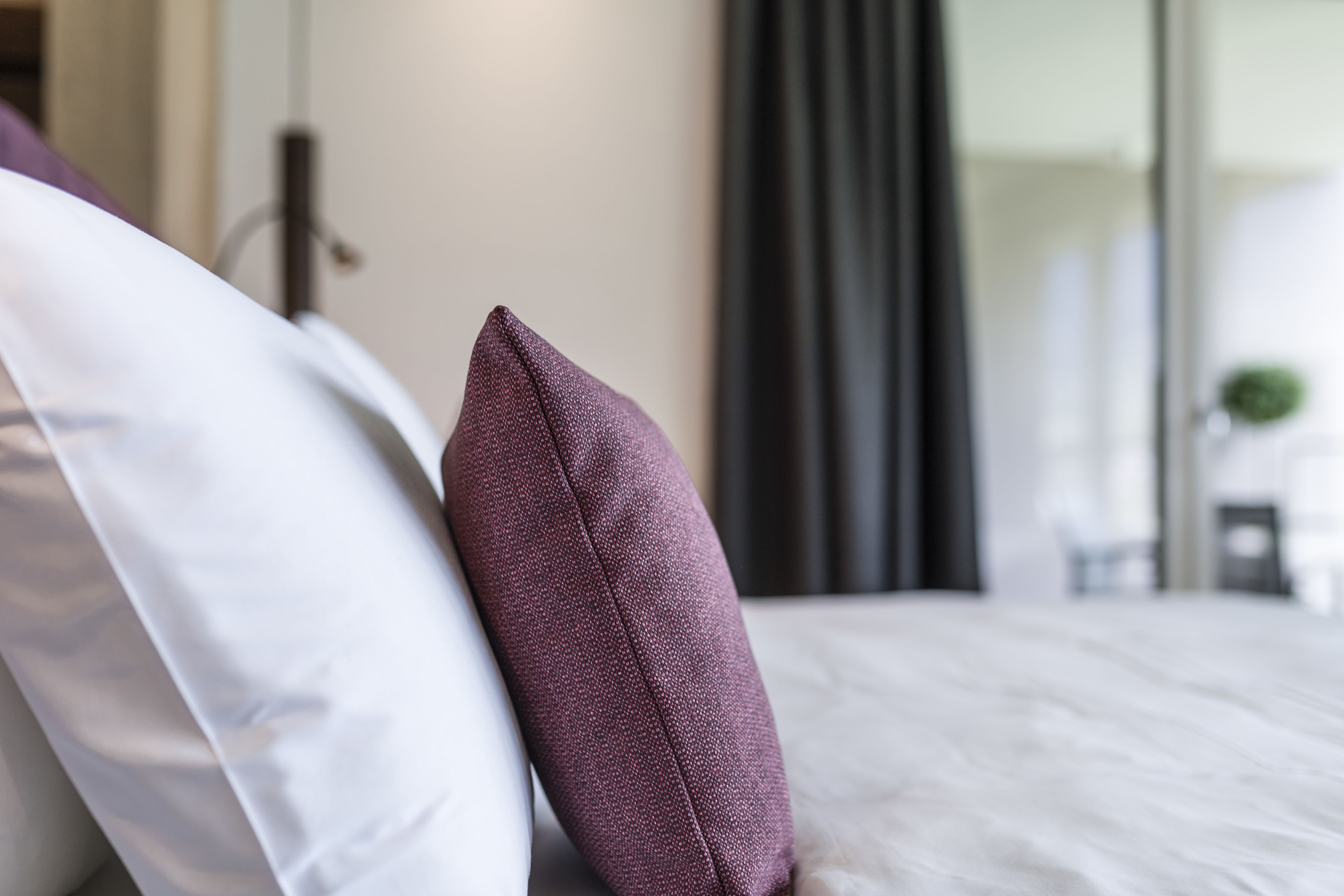 Ein Bett mit weißen und lilafarbenen Kissen.