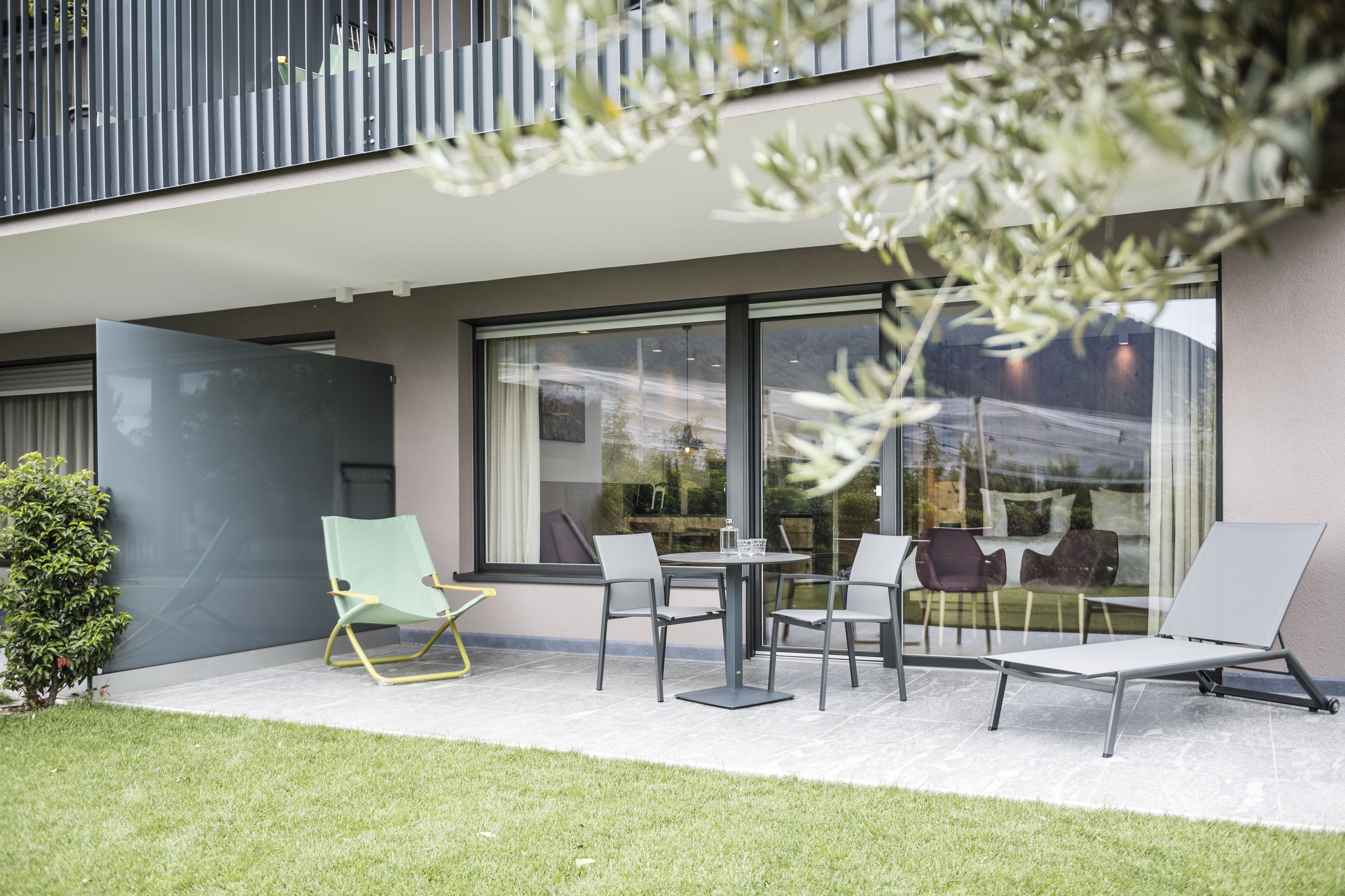 Un área de estar moderna al aire libre con una mesa, sillas, un vidrio y un balcón.