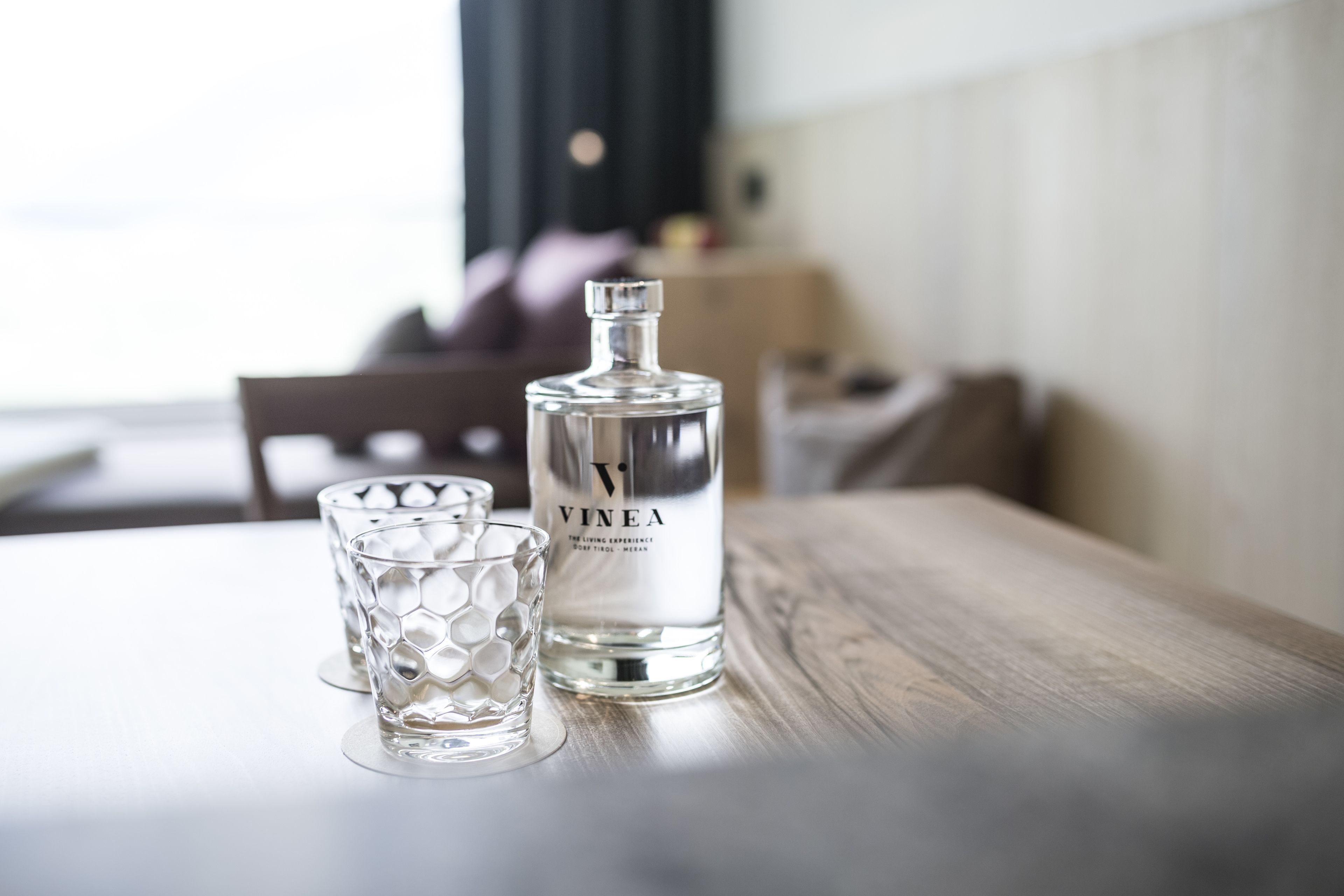 En flaska Vinea står på ett träbord tillsammans med ett glas.