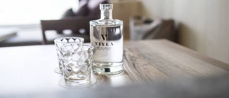 En flaska Vinea står på ett träbord tillsammans med ett glas.