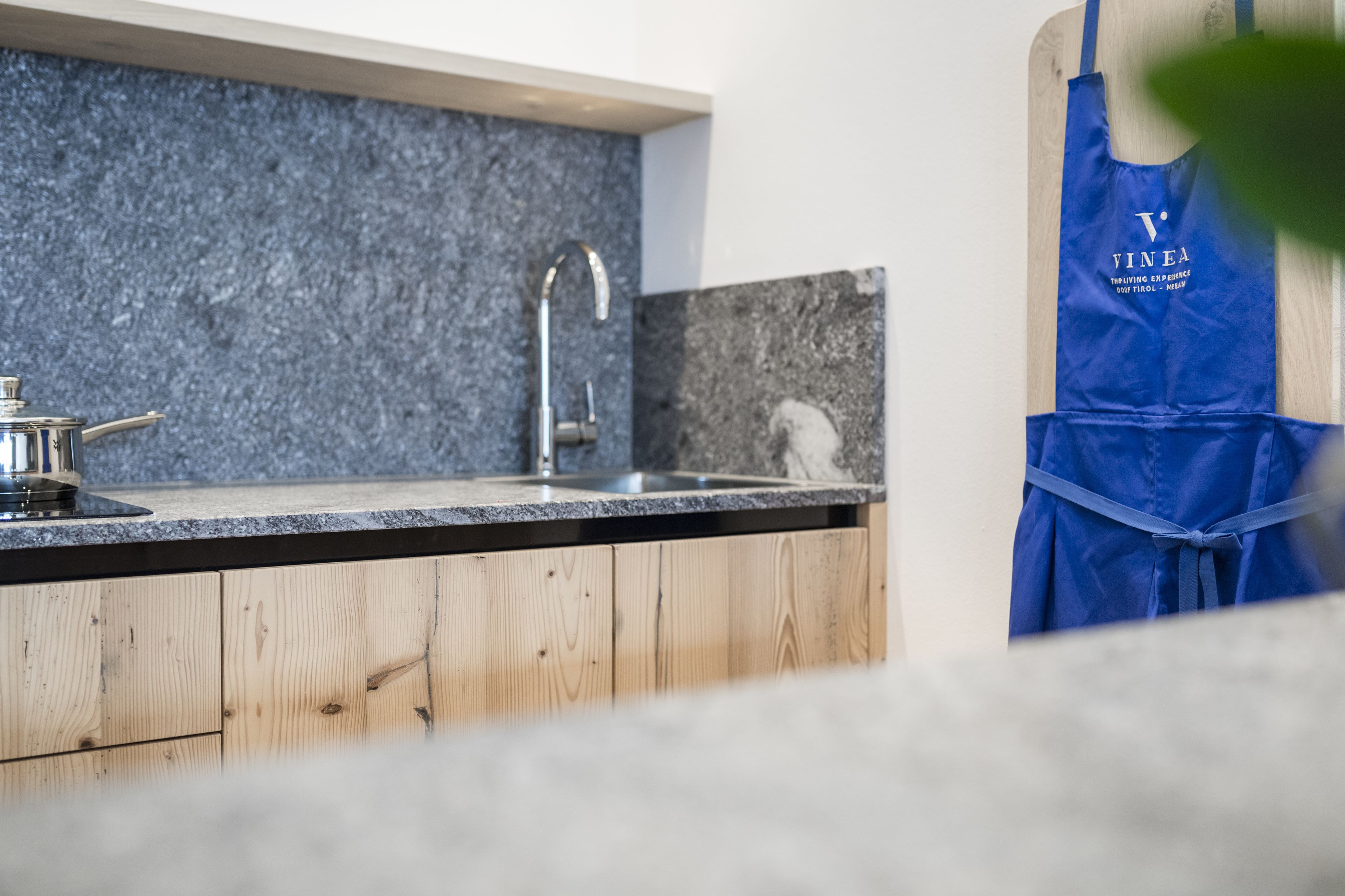 A modern kitchen with a granite countertop, stainless steel sink, and wooden cabinets.