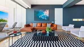 Un salon moderne avec un canapé d’angle, une table basse et une grande œuvre d’art accrochée au mur.
