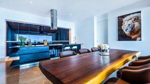 A modern kitchen with a large island, a dining area with a long wooden table, and a framed animal print on the wall. - Avalon - 907 (Puerto Vallarta)