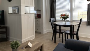 A modern living room with a dining area, white paneled walls, a ceiling fan, and a view through large windows with blinds. - C5, Flagler location in downtown, close to beaches, private patio, free parking! (St. Augustine)