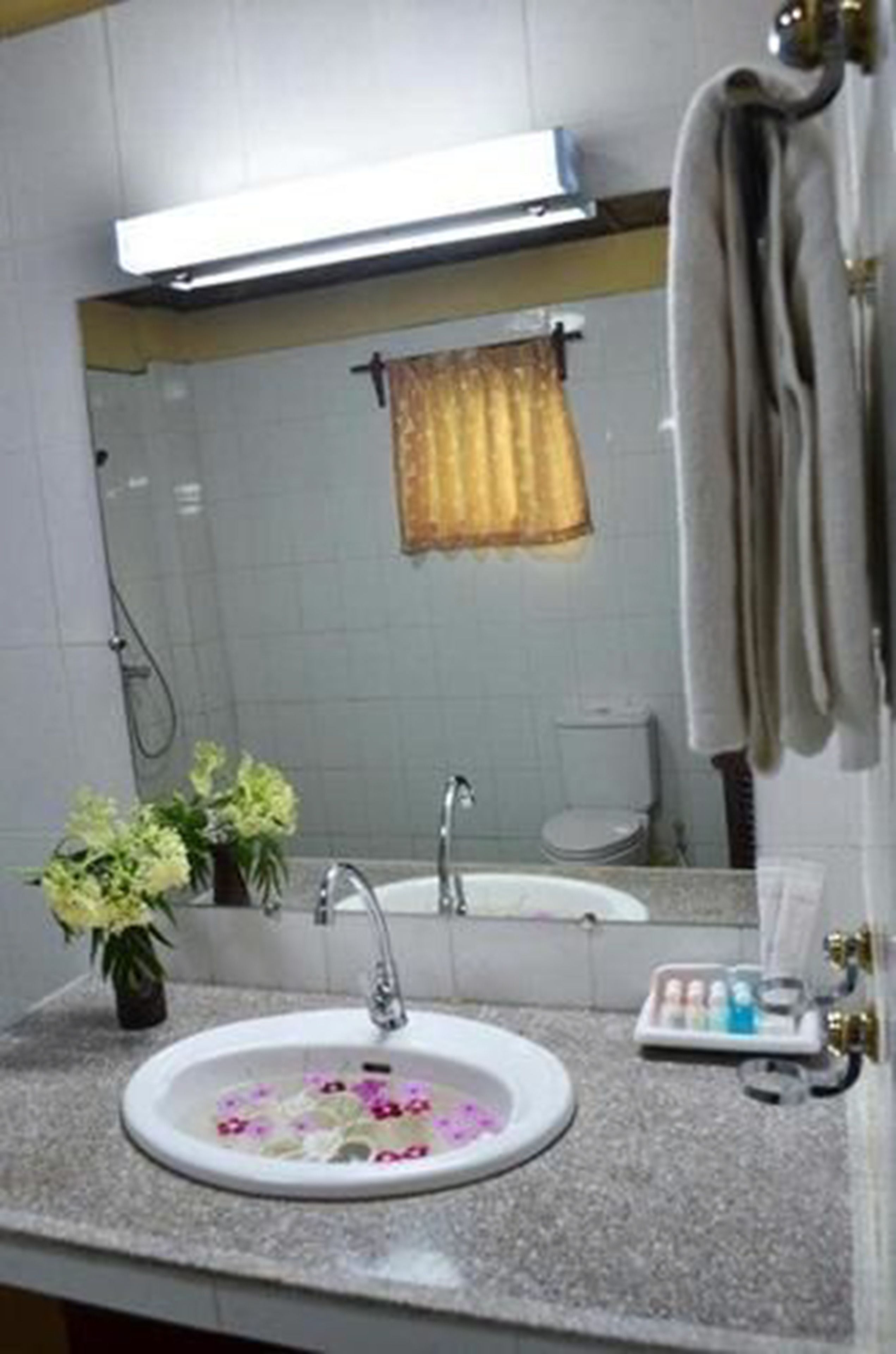 Un baño con lavamanos, espejo, toallero y ducha.