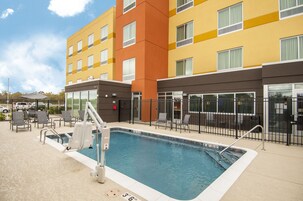A hotel with a pool area, outdoor seating, and a multi-story building with yellow and orange facades.