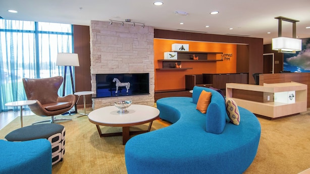 A modern living room with a stone fireplace, blue sofa, and a flat-screen TV. - Fairfield Inn & Suites by Marriott LaPlace (LaPlace)