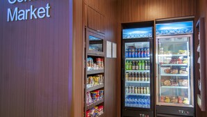 A corner market with refrigerated beverage and snack vending machines, wooden paneling, and a sign reading "the Corner Market". - Fairfield Inn & Suites by Marriott LaPlace (LaPlace)