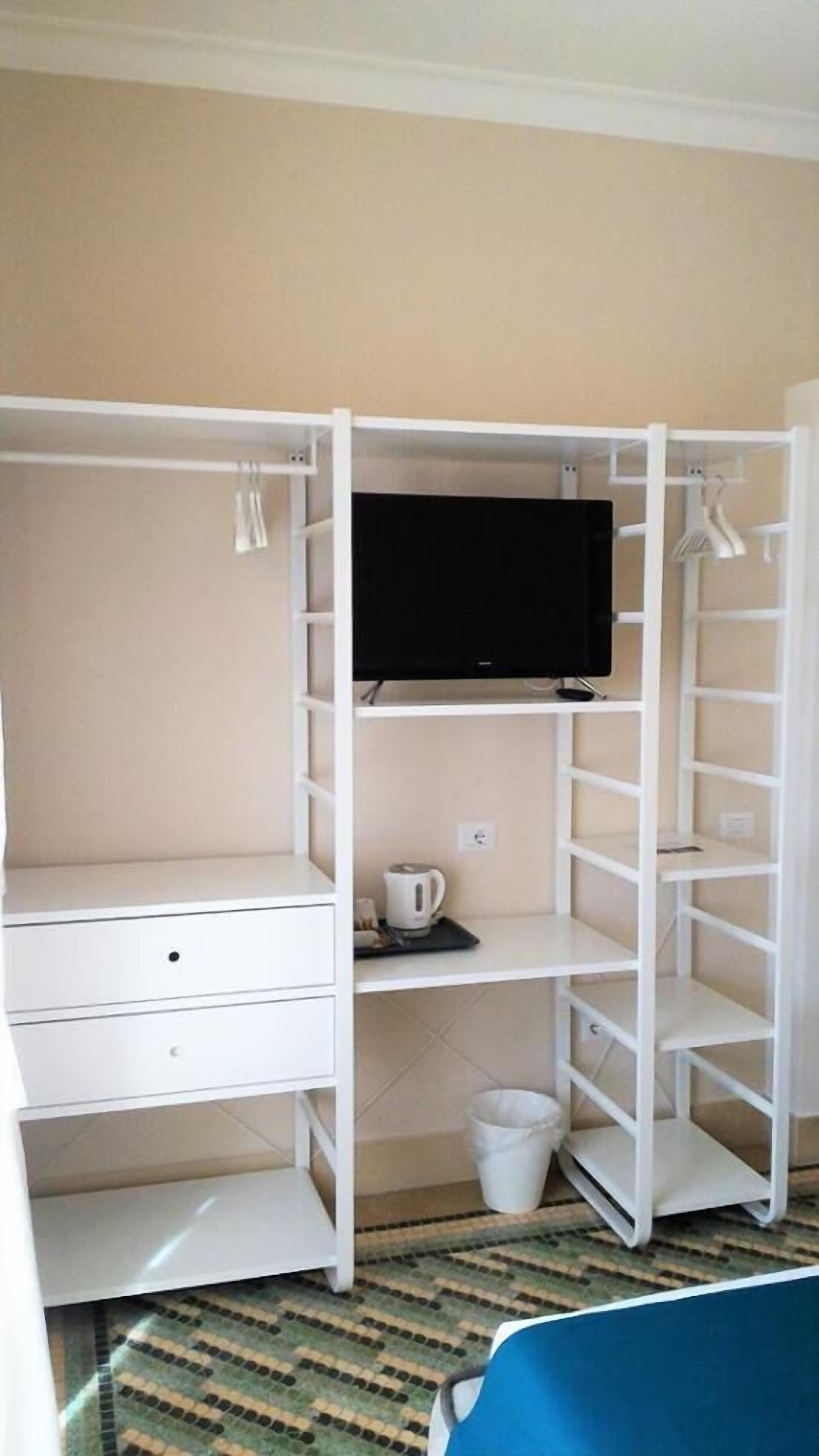 A compact room with a built-in TV, a small coffee table, and a trash bin.