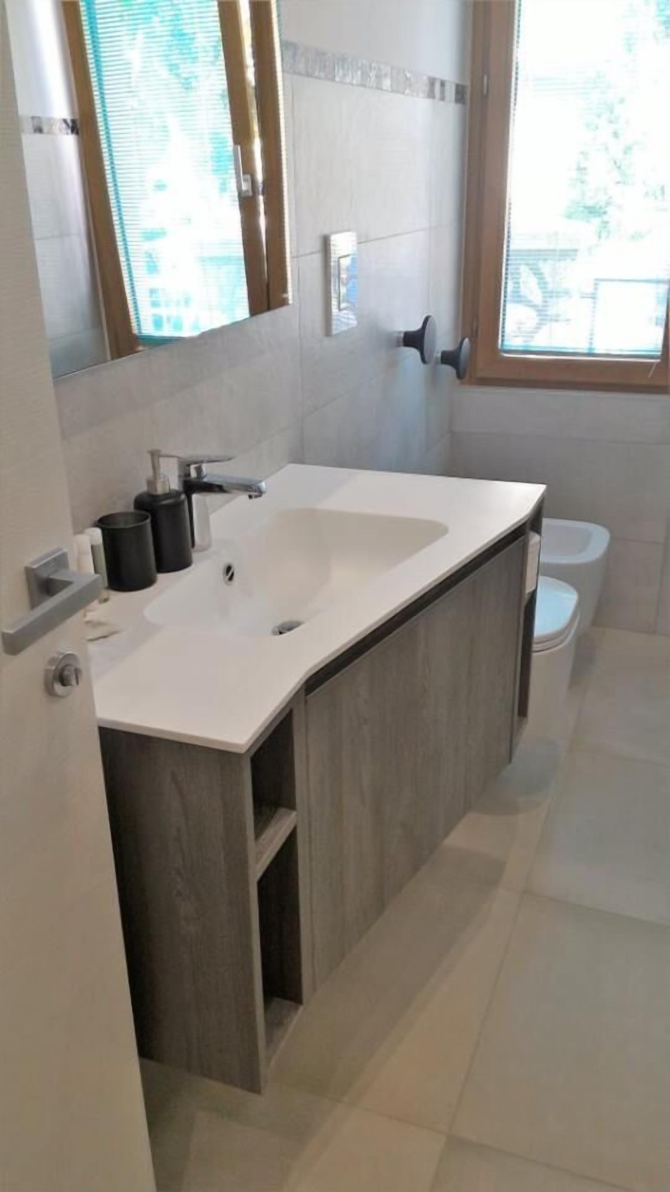 A modern bathroom with a white sink, wooden vanity, and a toilet.