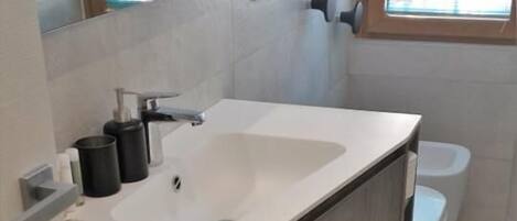 A modern bathroom with a white sink, wooden vanity, and a toilet.