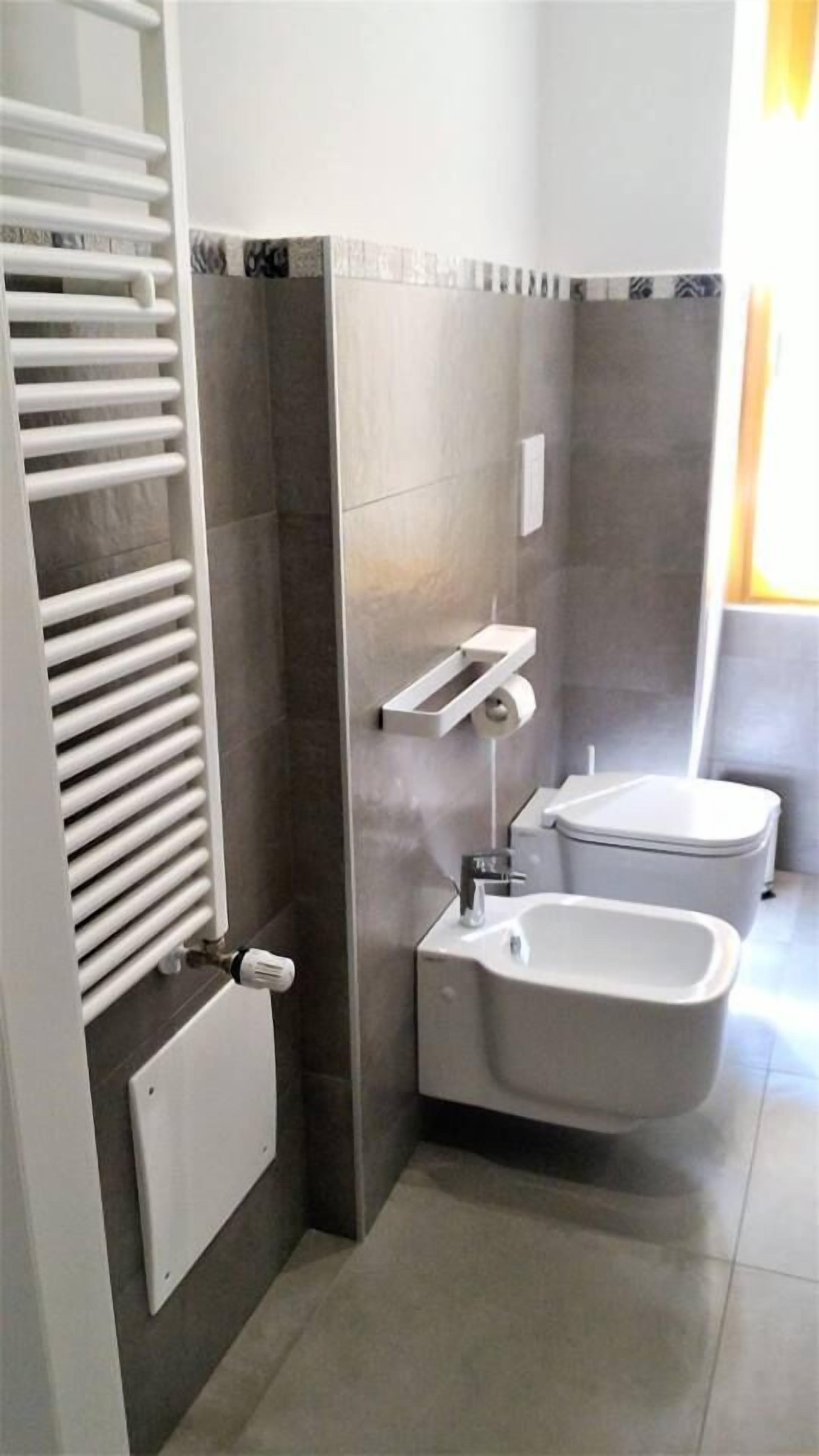 A modern bathroom with a built-in toilet, bidet, and a towel rack.