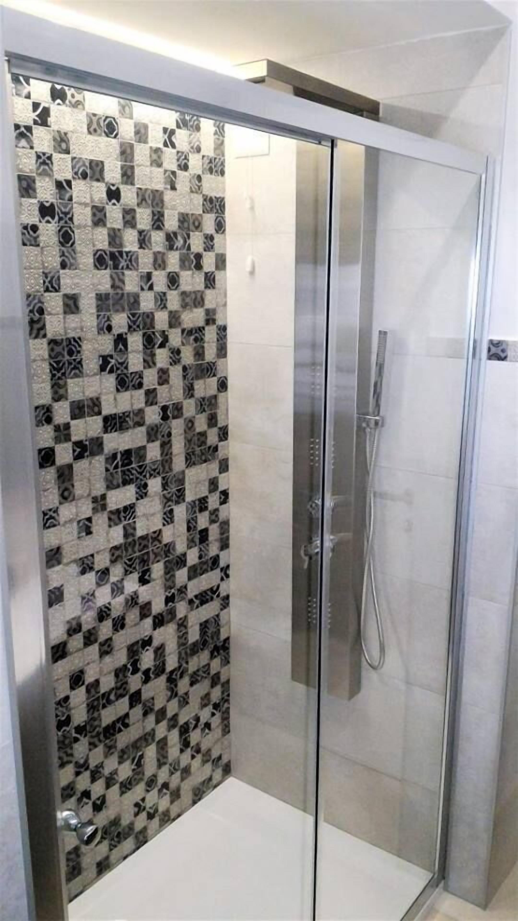 Een douchecabine met een glazen wand en een zwart-wit betegelde muur.