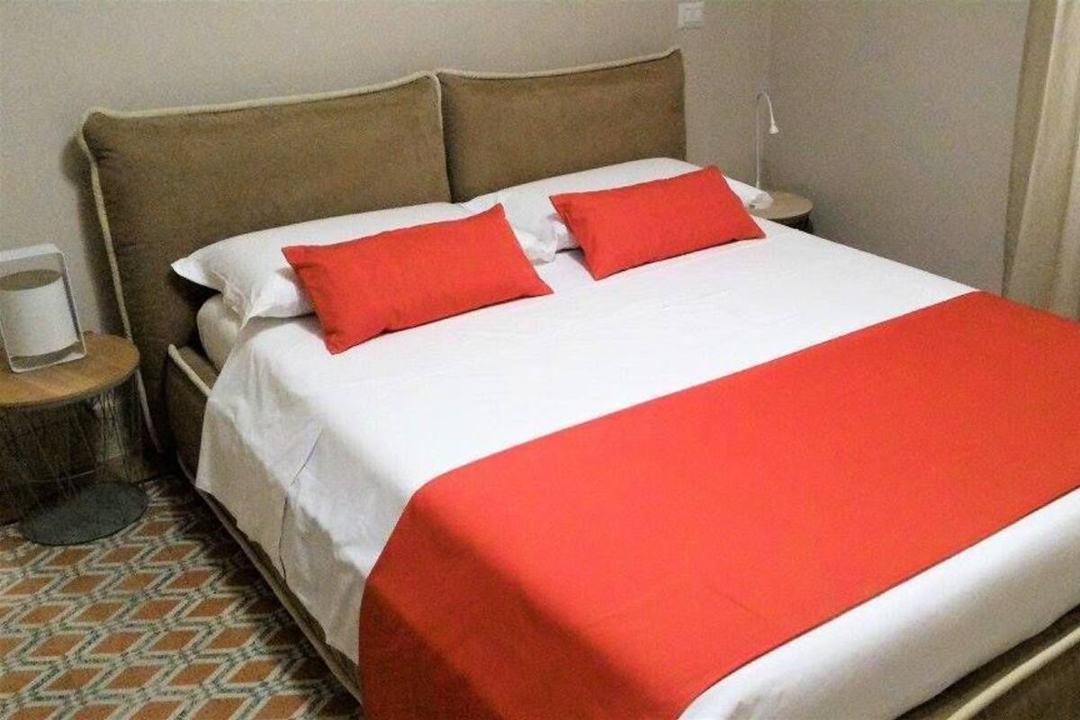 A bed with a white and red bedspread, two red pillows, and a wooden headboard.