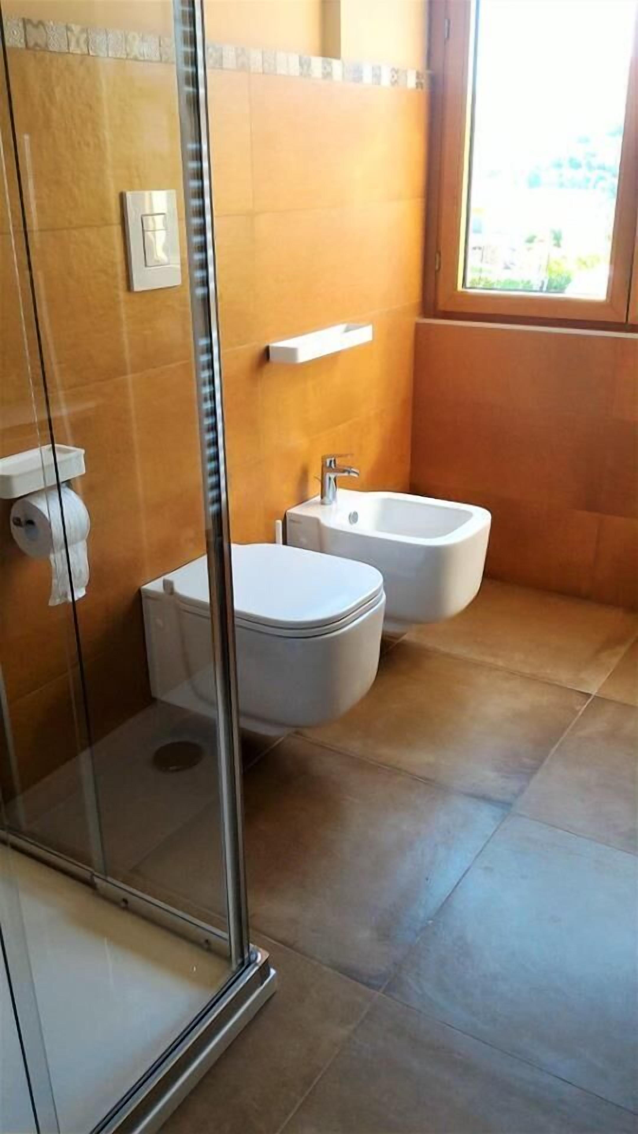 Un baño con cabina de ducha de vidrio, inodoro y bidé.