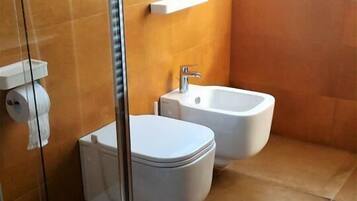 Un baño con cabina de ducha de vidrio, inodoro y bidé.