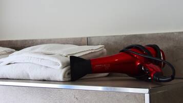 Un secador rojo sobre una encimera de baño junto a toallas dobladas.