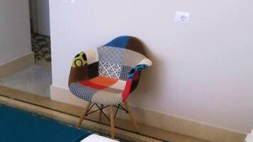 Una habitación con cama, almohadas, una silla y un papel tapiz estampado.